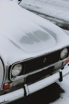 A retro vehicle's hood and bumper with snow, capturing winter nostalgia.