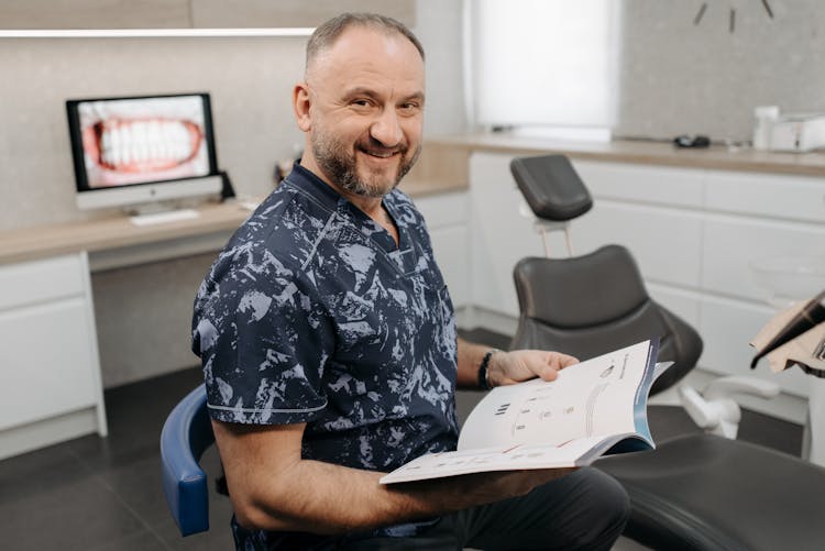 A Dentist Smiling And Holding A Book