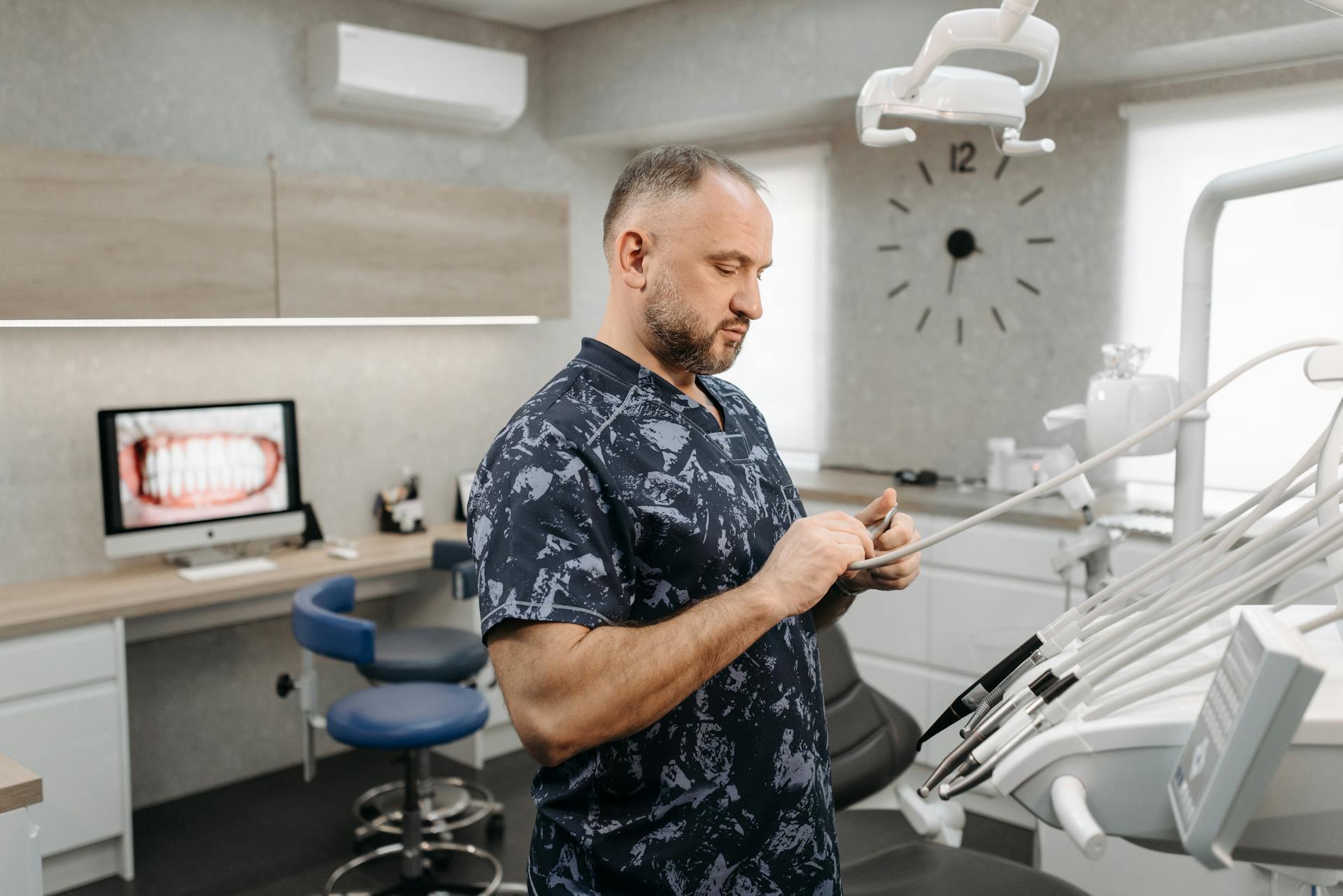 Dentist preparing dental tools in a modern dental office with equipment and patient images.