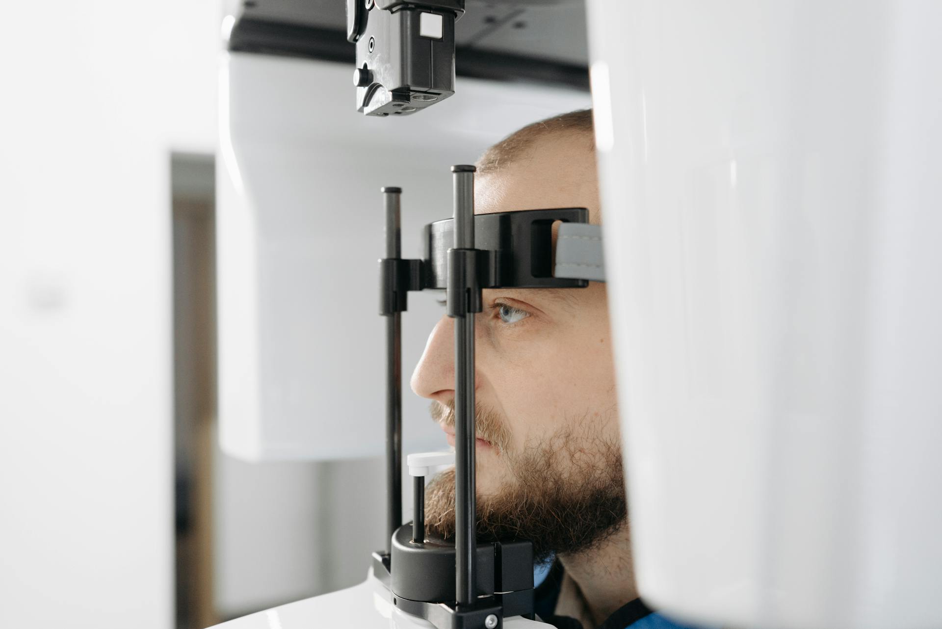 Side view of a man having an eye examination with a medical device in a healthcare setting.