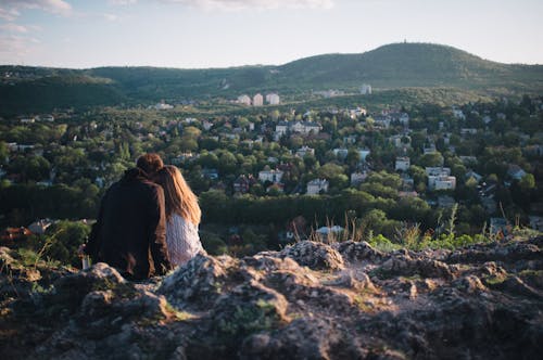 Couple Sitting Together on Rocks over Town in Forest