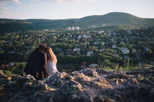 Free A couple enjoying a scenic view of Budapest from a rocky hilltop during the day. Stock Photo