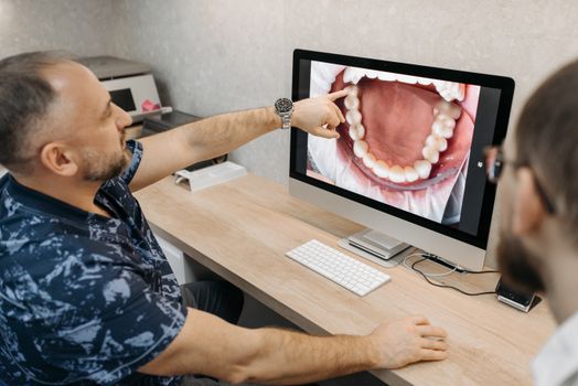 Dentist explains dental condition using intraoral images on a computer screen.