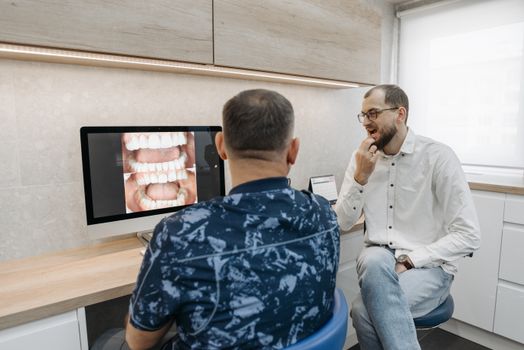 Dentist discussing dental x-ray results with patient in modern office setting.
