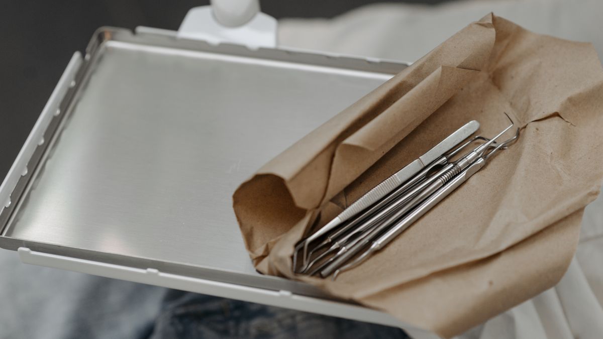 Close-up of dental tools wrapped in brown paper on a metal tray, highlighting dental care readiness.