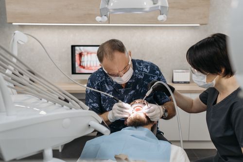 Free Dentist and assistant performing a dental procedure on a patient in a modern clinic. Stock Photo
