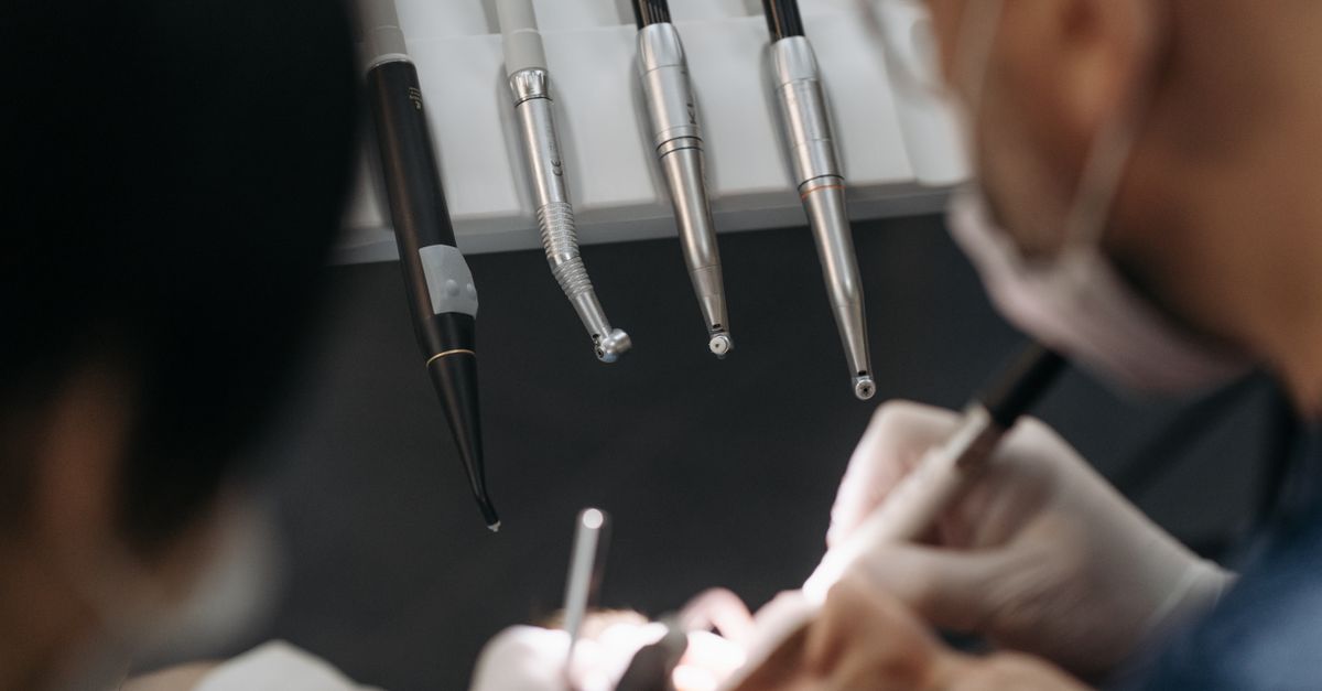 Close-up of dentists working on a patient with specialized dental instruments.