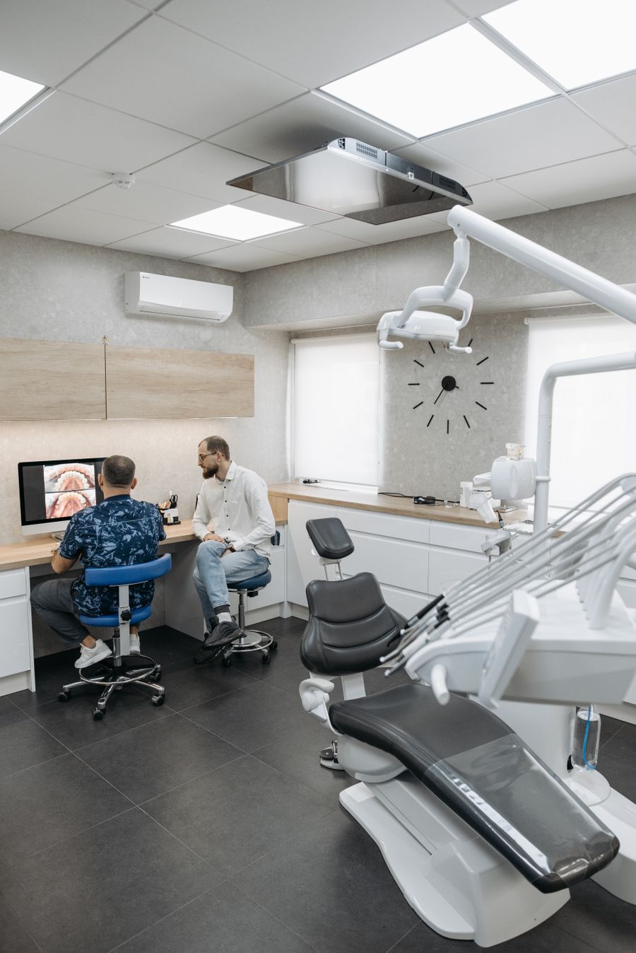 Dois dentistas discutindo um caso de planejamento em consultório moderno