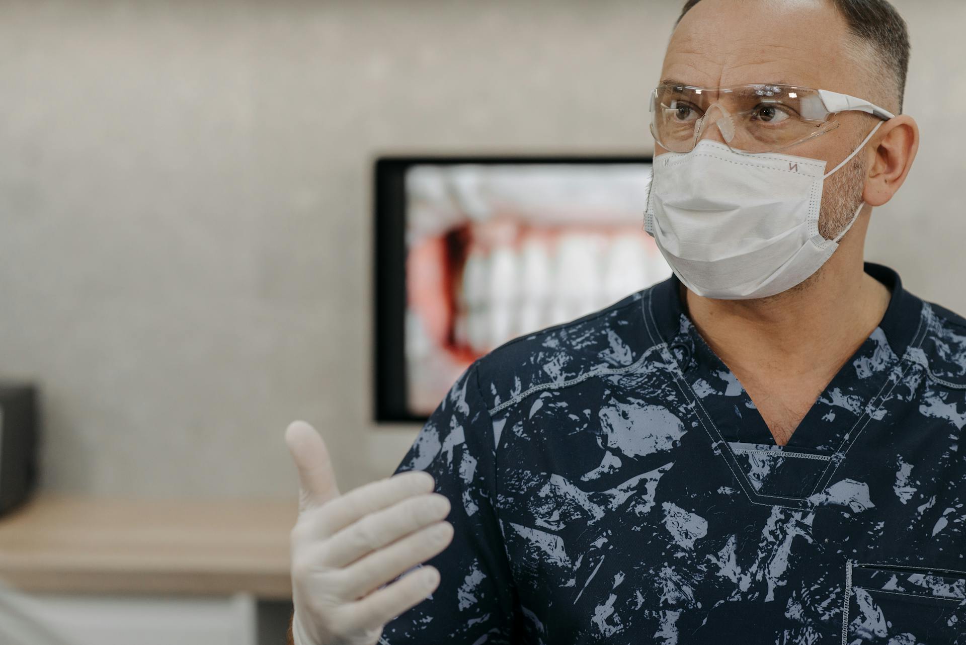 Healthcare worker with face mask and gloves in a medical setting, emphasizing safety.