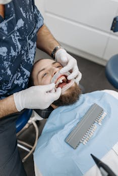 A dentist examines a patient's teeth using dental tools in a clinic setting.