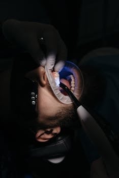 Vertical shot of a dental procedure using a curing light, highlighting patient care.