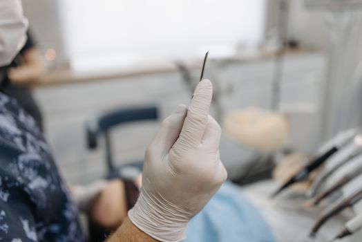 Dentist wearing gloves holds a precision tool in a dental clinic setting.
