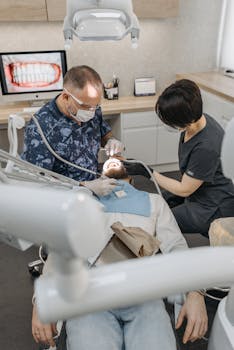 Dentist and assistant performing a dental procedure in a clinic with modern equipment.