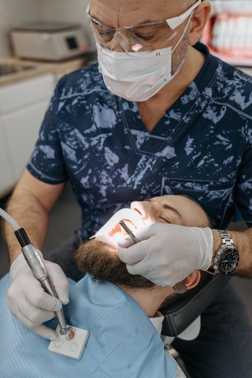 Free Dentist in protective gear performing dental procedure on patient in clinic. Stock Photo