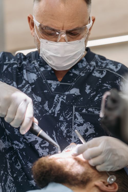 Free Dentist in protective gear conducting a dental procedure on a patient in a clinic setting. Stock Photo