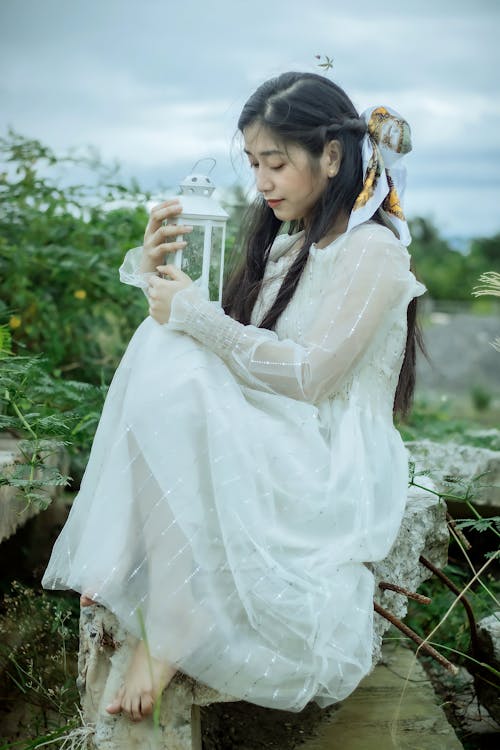 Asian lady in white dress on stones with lantern