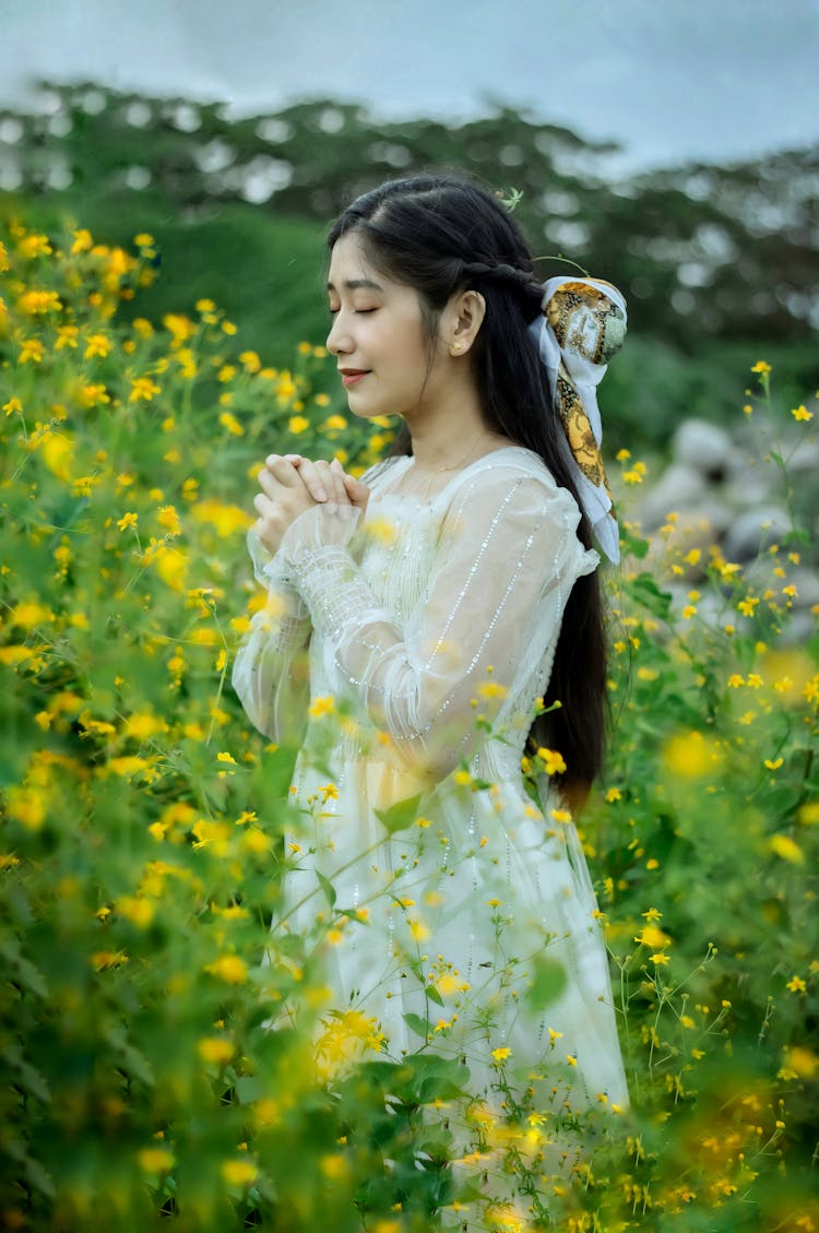 A Woman In A White Dress Surrounded By Yellow Flowers