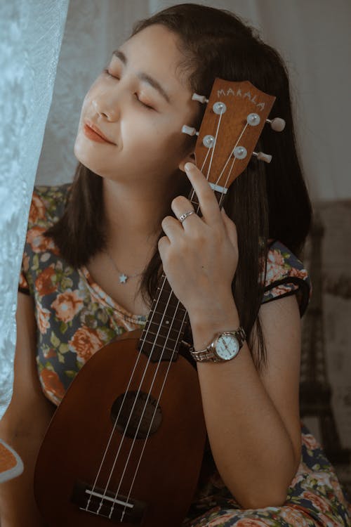 Free A Woman in a Floral Dress Holding a Ukelele Stock Photo