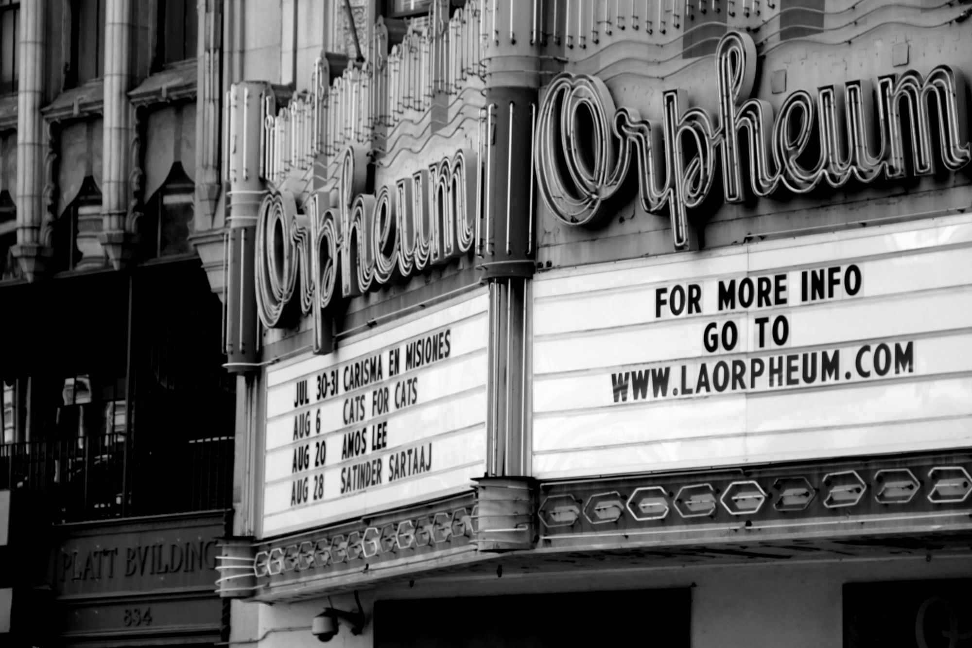 Fachada de un cine antiguo con marquesina iluminada, fotografía en blanco y negro