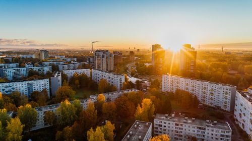 Free Aerial view of a cityscape at sunrise with autumn foliage and modern buildings. Stock Photo