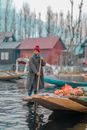 Man in Brown Jacket and Red Knit Cap Standing on Brown Wooden Boat on River during