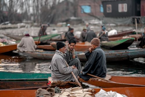 Free Group of men talking on boats in a calm water scene, showcasing local lifestyle. Stock Photo