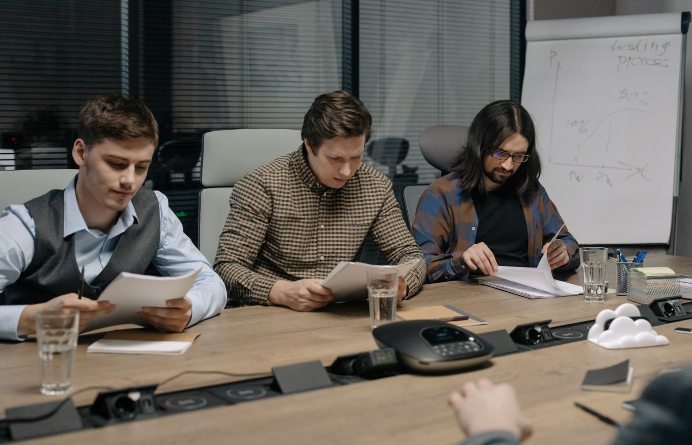 Three business colleagues reviewing documents in a modern conference room during a daytime meeting.