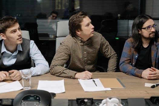 Three men engaged in a business meeting, focusing on a presentation.