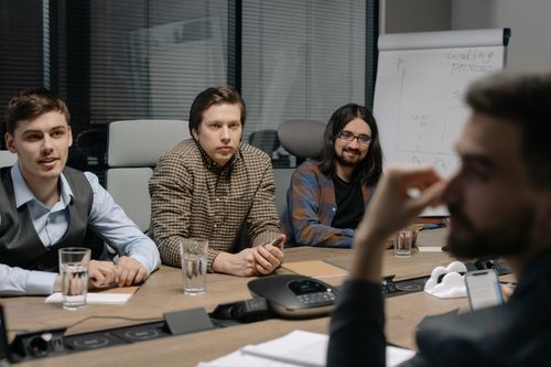 Free Professional team engaged in a business meeting at a conference table in a modern office environment. Stock Photo
