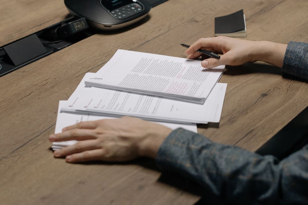 Annotated case papers spread across a wooden meeting table — photo by cottonbro studio on Pexels