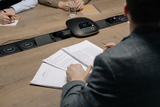 Close-up of business professionals reviewing documents during a meeting in a modern office setting.