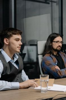 Men engaged in a business discussion at an office desk with documents.