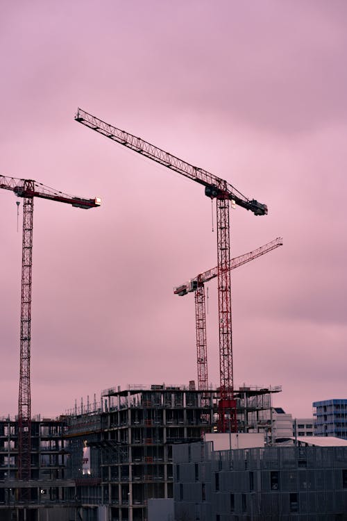 Tower Cranes Under Cloudy Sky