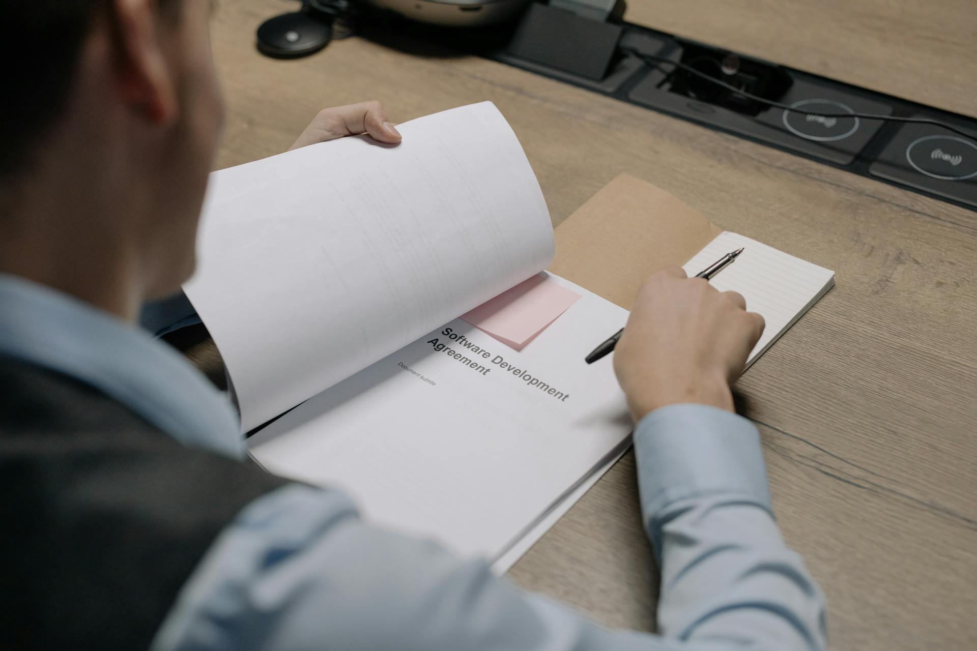 Business professional at the desk examining a software development agreement document.