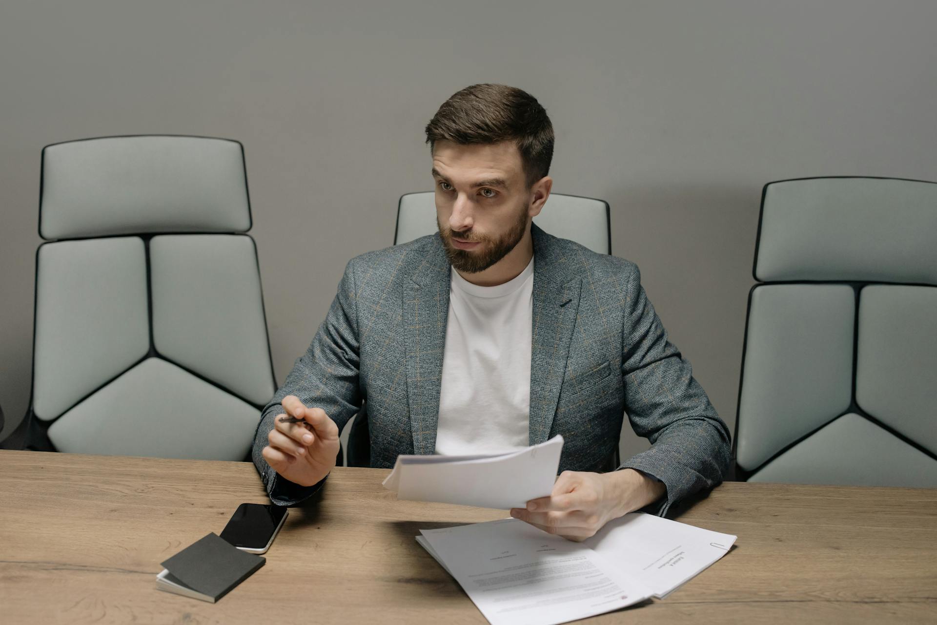 Professional businessman in a suit holding documents during a meeting in an office setting.