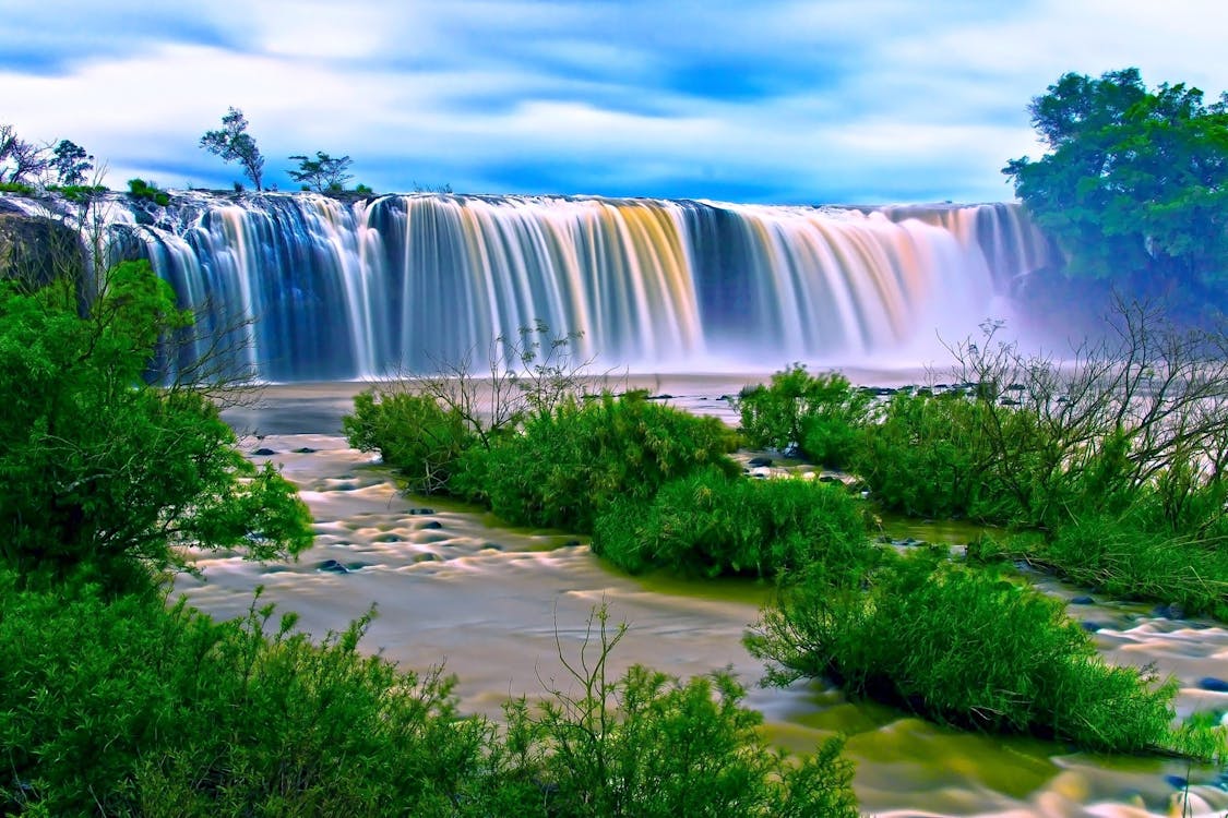 Water Falls Surrounding Green Grass during Daytime