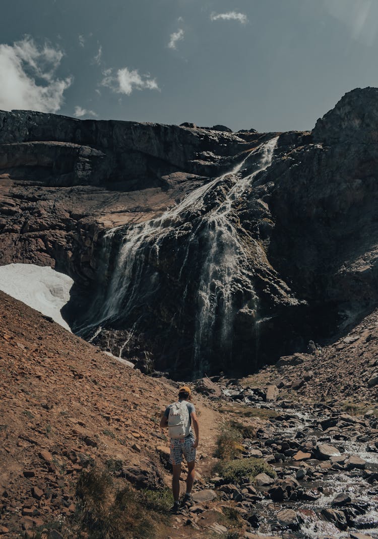 Back View Of A Man Hiking On A Mountain With Stream