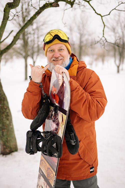 Man in Orange Jacket Holding a Snowboard