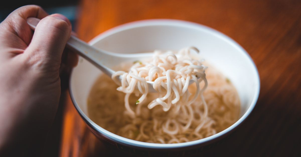 student backpacker cooking instant noodles in a cramped dorm kitchen