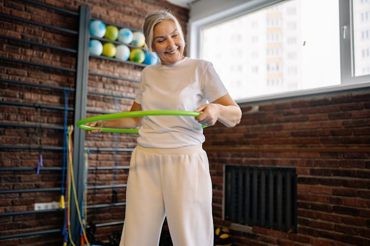 An Elderly Woman Using A Hula Hoop