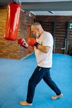 Elderly man boxing indoors, focusing on fitness and technique.