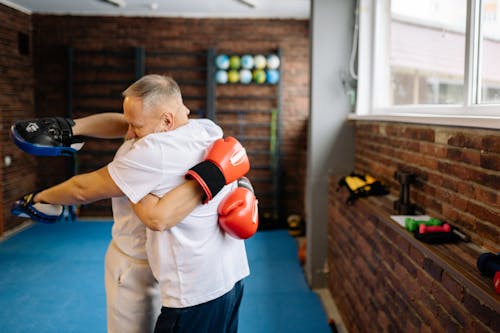 Free A Person Wearing a Boxing Glove Hugging a Man with Hit Pads Stock Photo