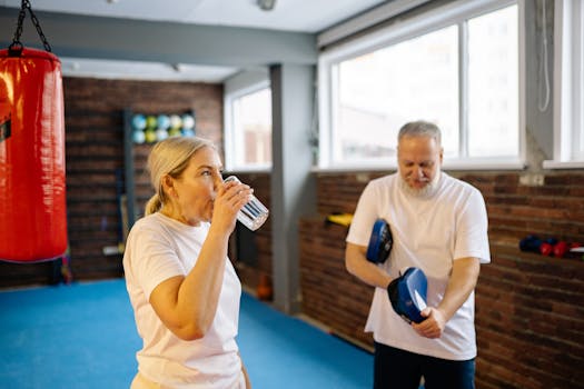 Two senior adults engaging in a fitness routine indoors, using focus mitts for exercise.