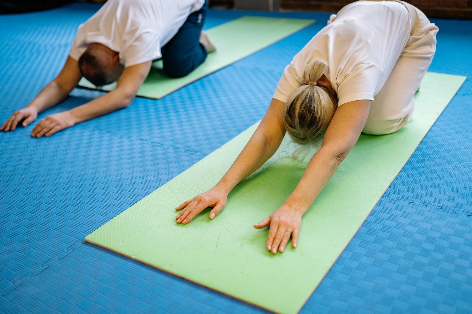 Senior adults stretching on yoga mats inside a gym, promoting health and fitness.