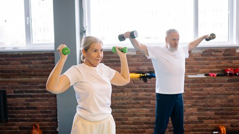 Elderly man and woman workout with dumbbells promoting healthy lifestyle and fitness.