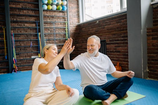 Energetic senior couple enjoying yoga, sharing a joyful high-five at the gym.