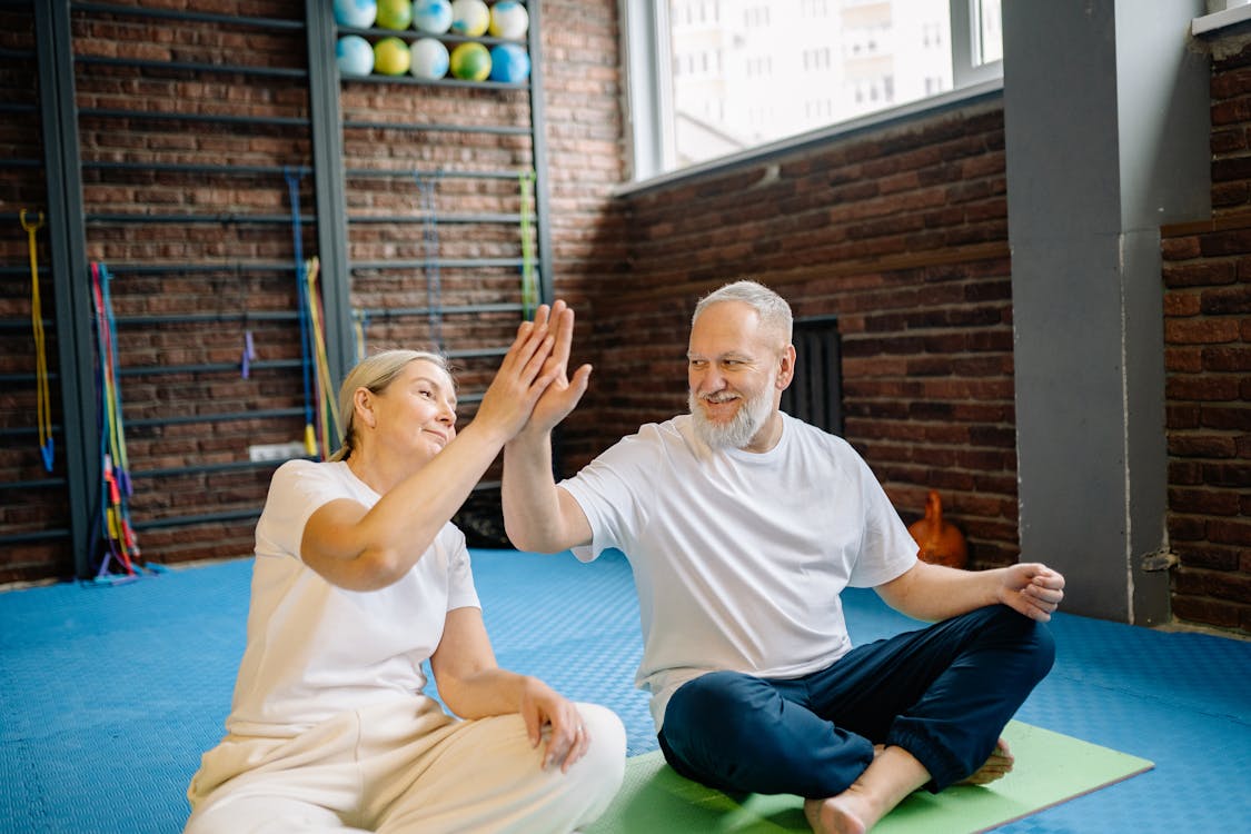 Man in White Crew Neck T-shirt and Blue Shorts Sitting on Blue Yoga Mat