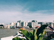 夏日阳光明媚，城市的天际线映在河面上，船只和旗帜点缀其间