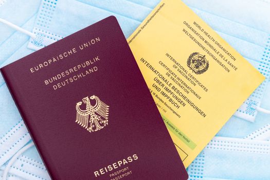 German passport, vaccination card on masks symbolizing travel and health.