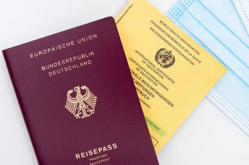 Free Close-up of a German passport, vaccination card, and mask, symbolizing travel and health safety. Stock Photo